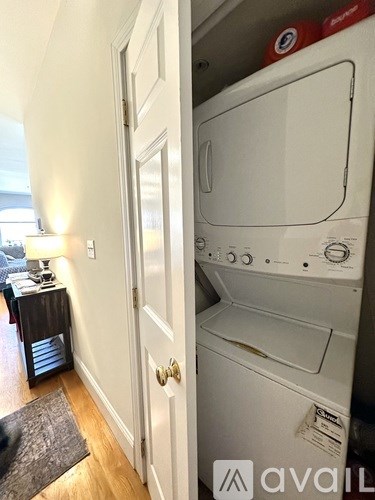 A white dishwasher is in a narrow hallway.
