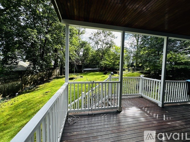 A wooden deck with a white railing overlooks a grassy area.