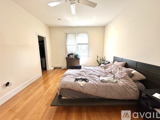 A bedroom with a bed, a ceiling fan, and a window.