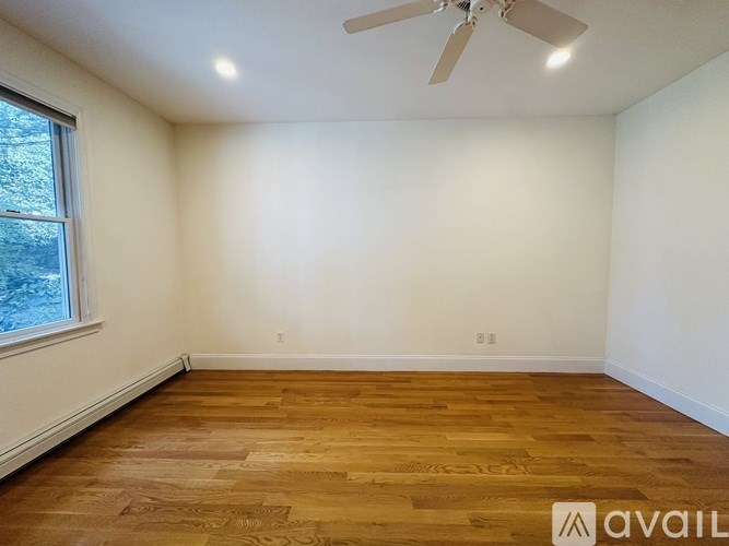 A room with a desk and a computer, a fan, and a rug.