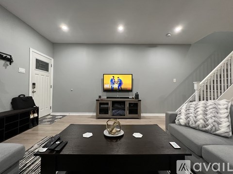 A living room with a television on a stand and a couch with a pillow.