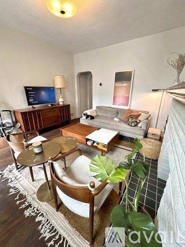 A living room with a white couch, a wooden coffee table, and a TV on a wooden cabinet.