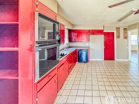 A kitchen with red cabinets and a white microwave.