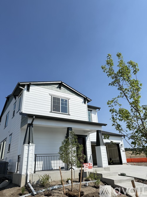 A white house with a black roof and a grey roof extension is available for sale.