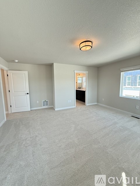 A spacious room with a carpeted floor and a ceiling light.