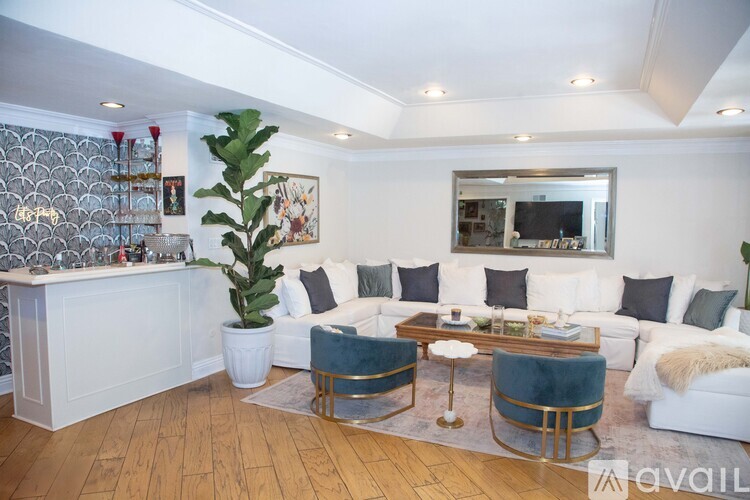 A living room with a white couch, a wooden table, and a large plant.