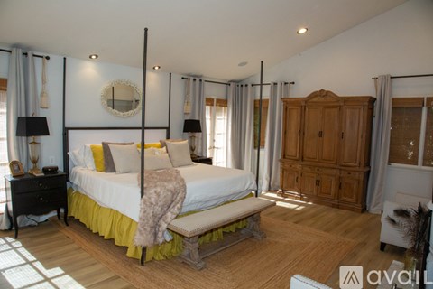 A bedroom with a four poster bed and a wooden wardrobe.