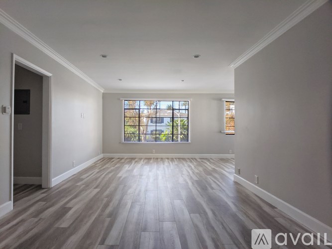 A spacious room with wooden flooring and a large window.