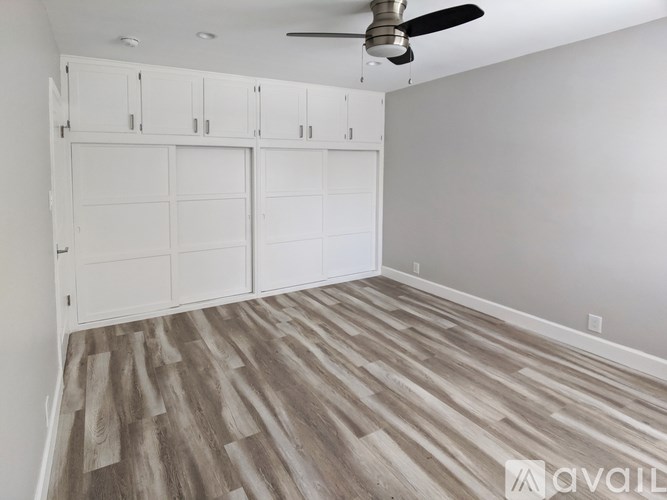 A room with a ceiling fan and wooden flooring.