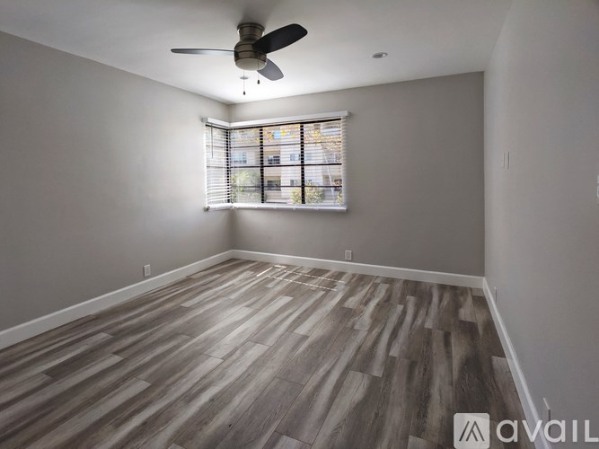 A room with a ceiling fan and wooden flooring.