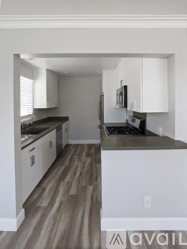 A kitchen with white cabinets and a wooden floor.
