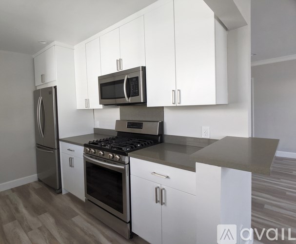 A kitchen with white cabinets and a stainless steel refrigerator.