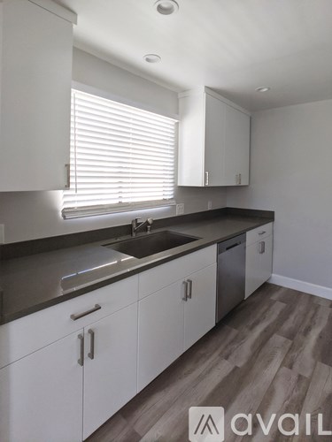 A kitchen with white cabinets and a sink under a window.