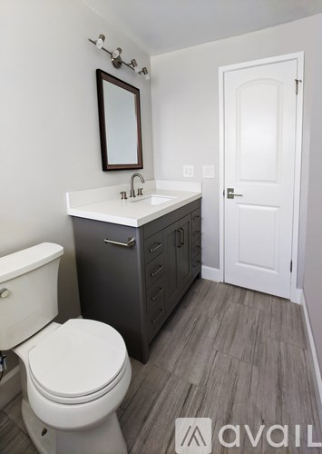 A bathroom with a toilet, sink, and mirror.