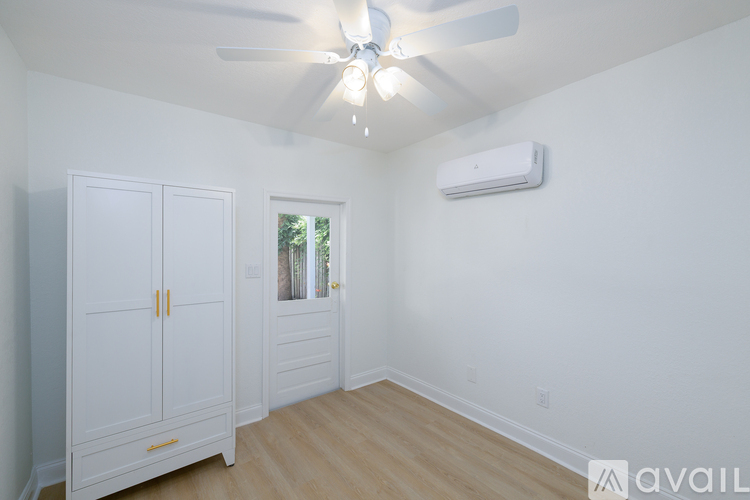 A room with a ceiling fan and a window with a view of trees.