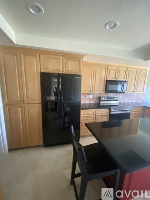 A kitchen with wooden cabinets and a black fridge.