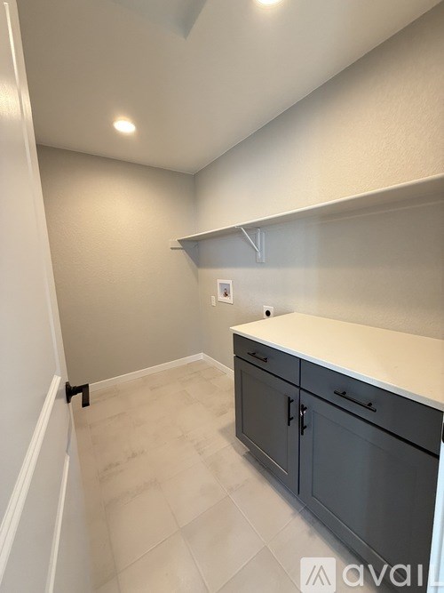 A kitchen with white countertops and grey cabinets.