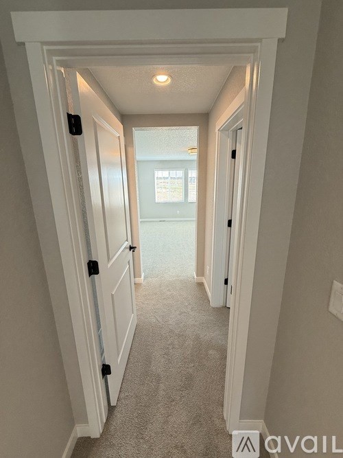 A hallway with a carpeted floor and white walls.