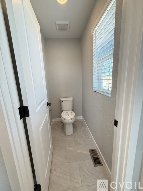 A white toilet in a small bathroom with a window.