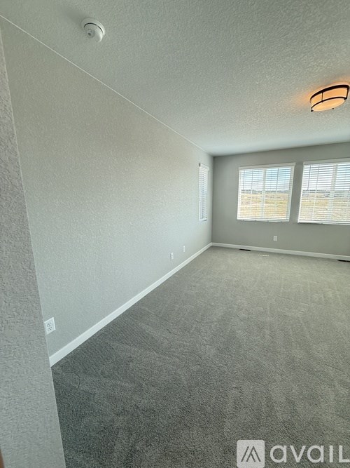 A room with carpeted floor and a window with blinds.