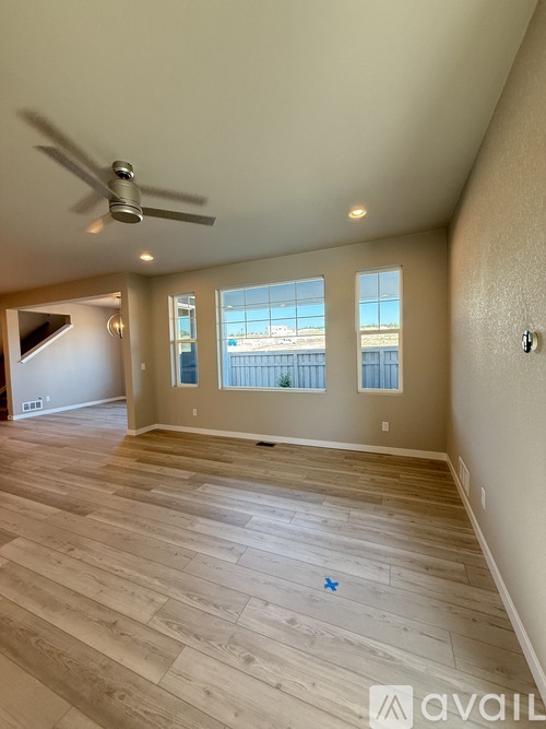 A spacious room with a ceiling fan and wooden flooring.