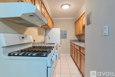 A kitchen with a white stove and wooden cabinets.