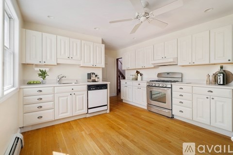 A kitchen with white cabinets and wooden floors.