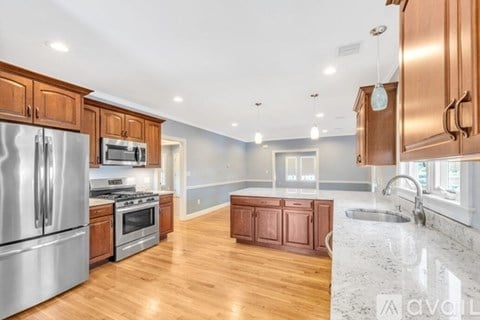 A kitchen with wooden cabinets and stainless steel appliances is available for rent.