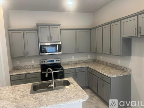 A kitchen with a sink, stove, and microwave.