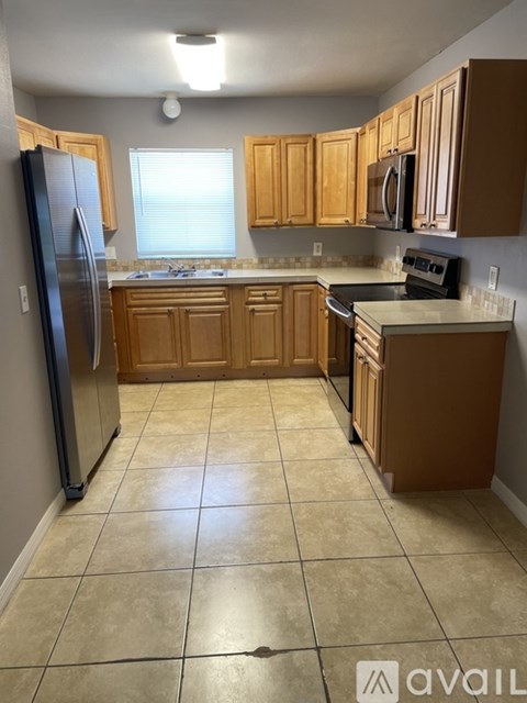 A kitchen with wooden cabinets and a black refrigerator.