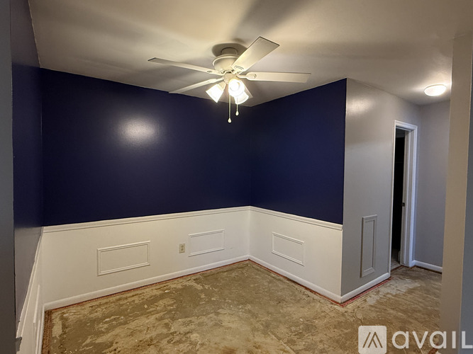 A room with a carpeted floor and a ceiling fan.