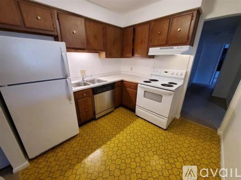 A kitchen with a white refrigerator, white stove, and yellow tiled floor.
