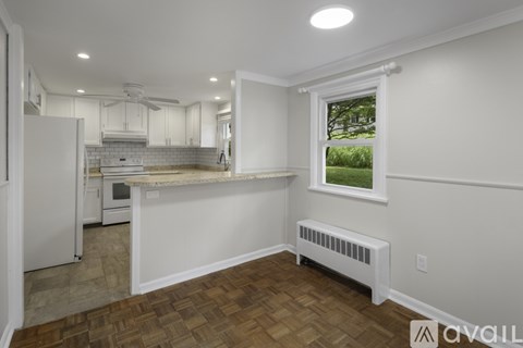 A kitchen with white cabinets and a window overlooking a green lawn.