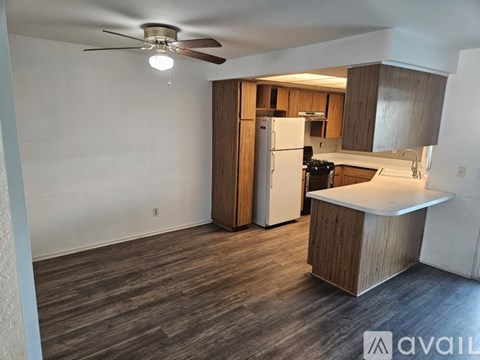 A kitchen with a refrigerator, oven, and a ceiling fan.