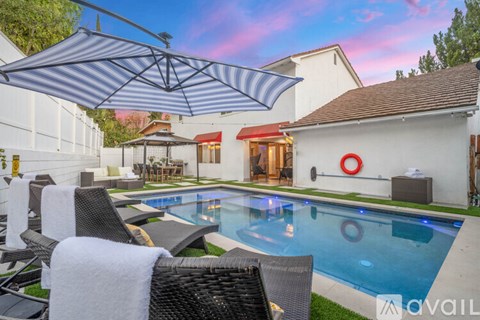 A pool with a white umbrella and chairs.