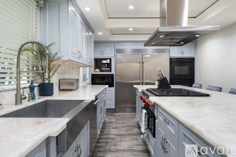 A modern kitchen with stainless steel appliances and marble countertops.