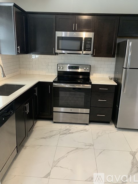 A kitchen with black cabinets and a stainless steel refrigerator.