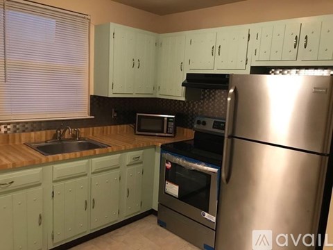 A kitchen with green cabinets and a stainless steel refrigerator.