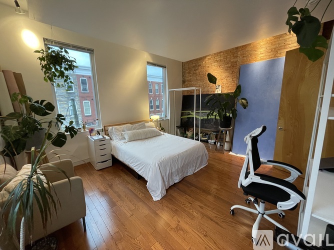 A bedroom with a bed, chair, and potted plants.