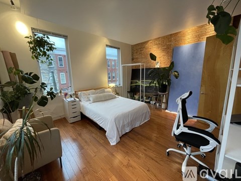 A bedroom with a bed, chair, and potted plants.
