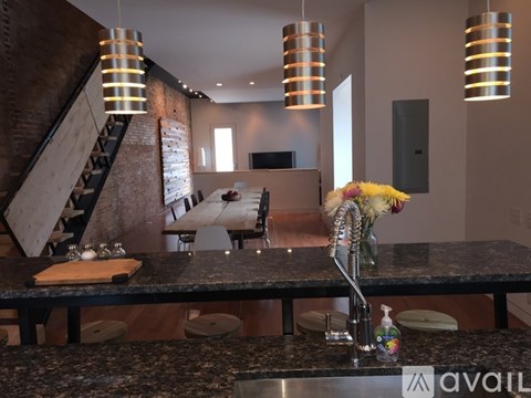 A kitchen with a granite countertop and a staircase in the background.