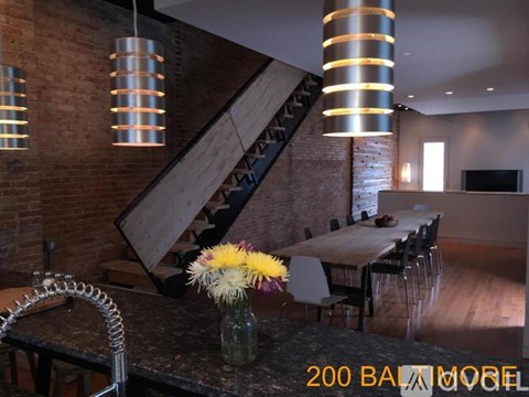 A dining room with a brick wall and a spiral staircase.