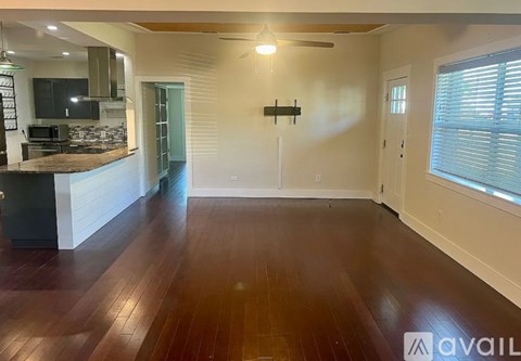 A room with wooden floors and a kitchen area with a counter and cabinets.