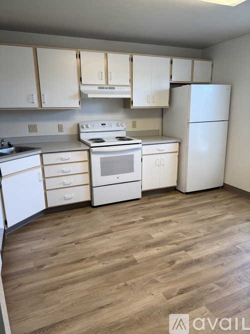 A kitchen with white appliances and wooden floors.
