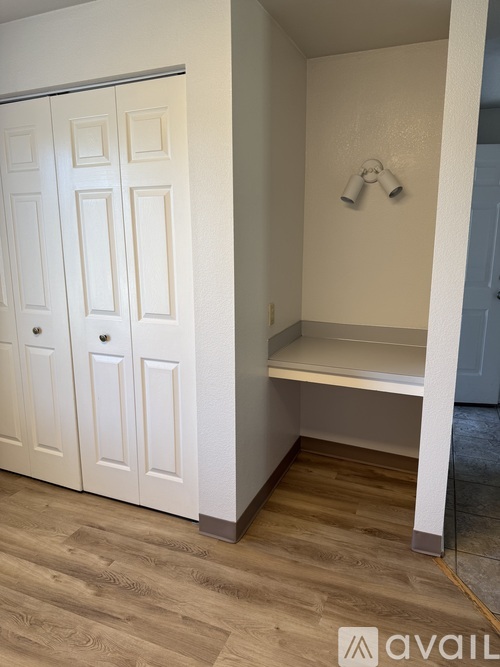 A white closet with a bench and a wooden floor.
