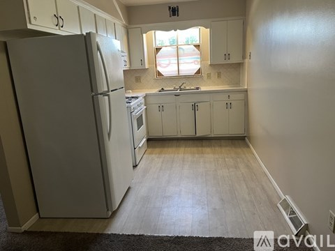 A kitchen with white appliances and cabinets.