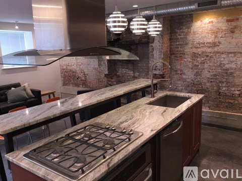 A kitchen with a stove top oven and a brick wall.