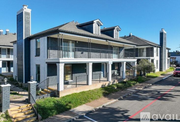 A modern house with a large front porch and a red car parked on the street.