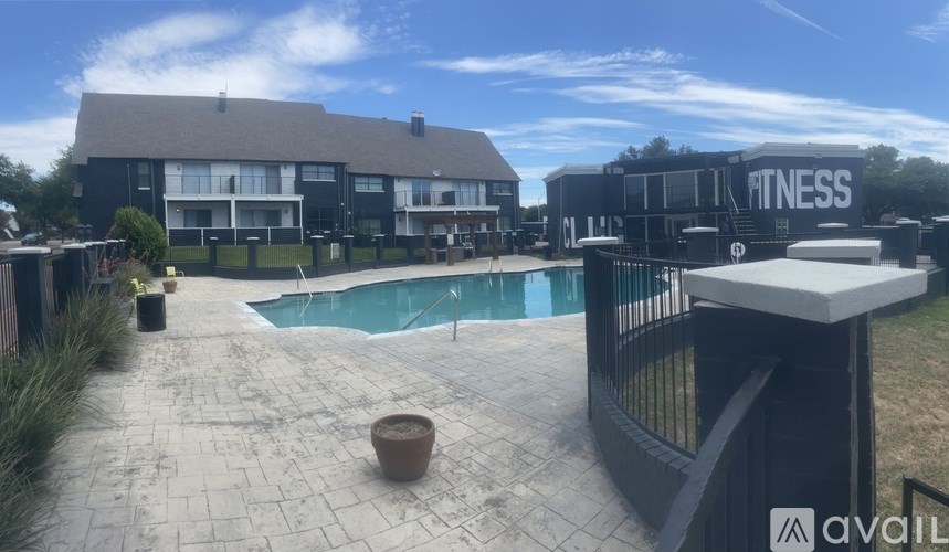 A black building with the word "FITNESS" on it is next to a pool.