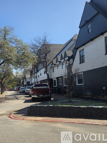 A street view with a building on the right and a tree in the middle of the road.